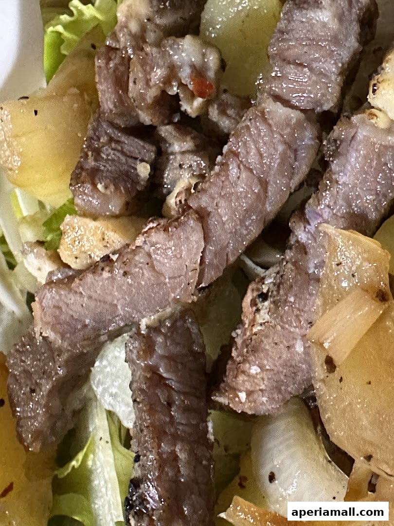 A close-up shot of a salad with sliced steak and potatoes.