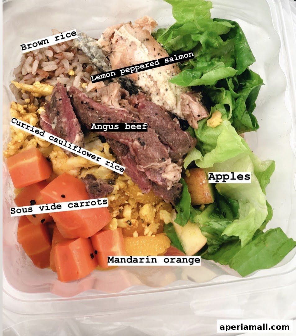 A healthy salad bowl with brown rice, salmon, beef, carrots, apples, and mandarin oranges.