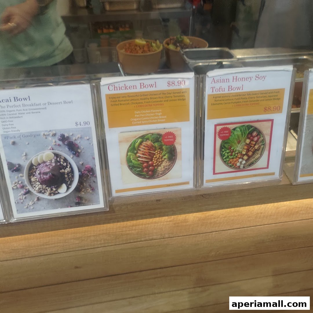 A display of three healthy bowl options with prices and descriptions at a salad bar.