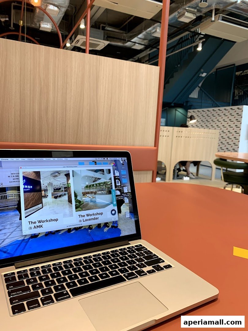 A laptop displays images of a modern interior space with wooden accents and industrial elements.