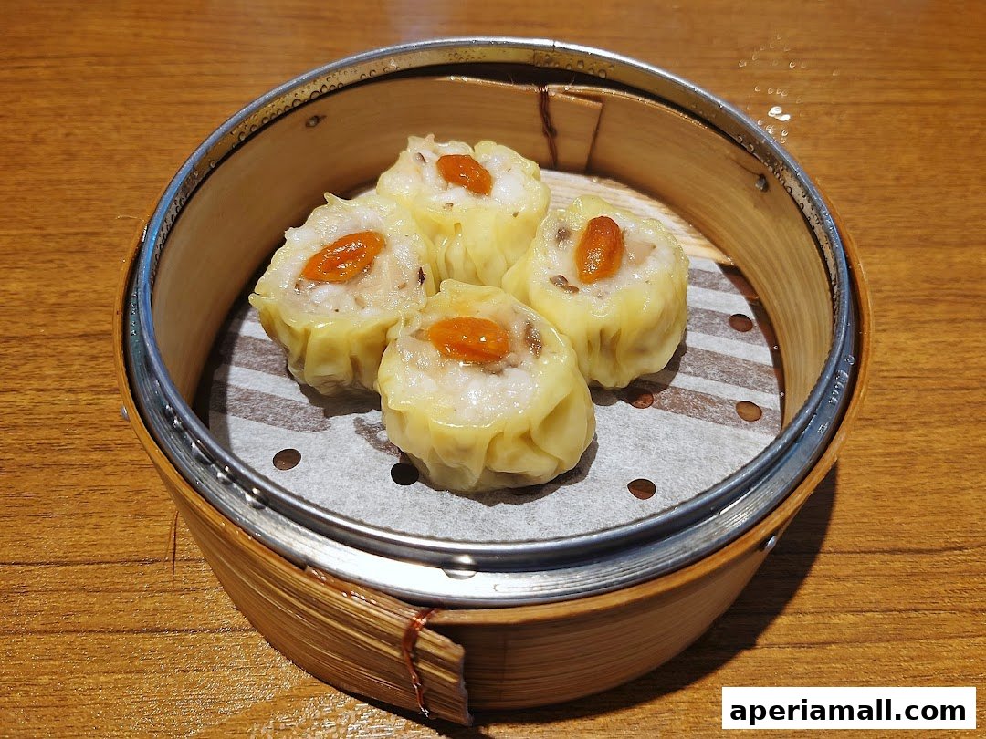 A close-up shot of four delicious dim sum dumplings in a bamboo steamer.