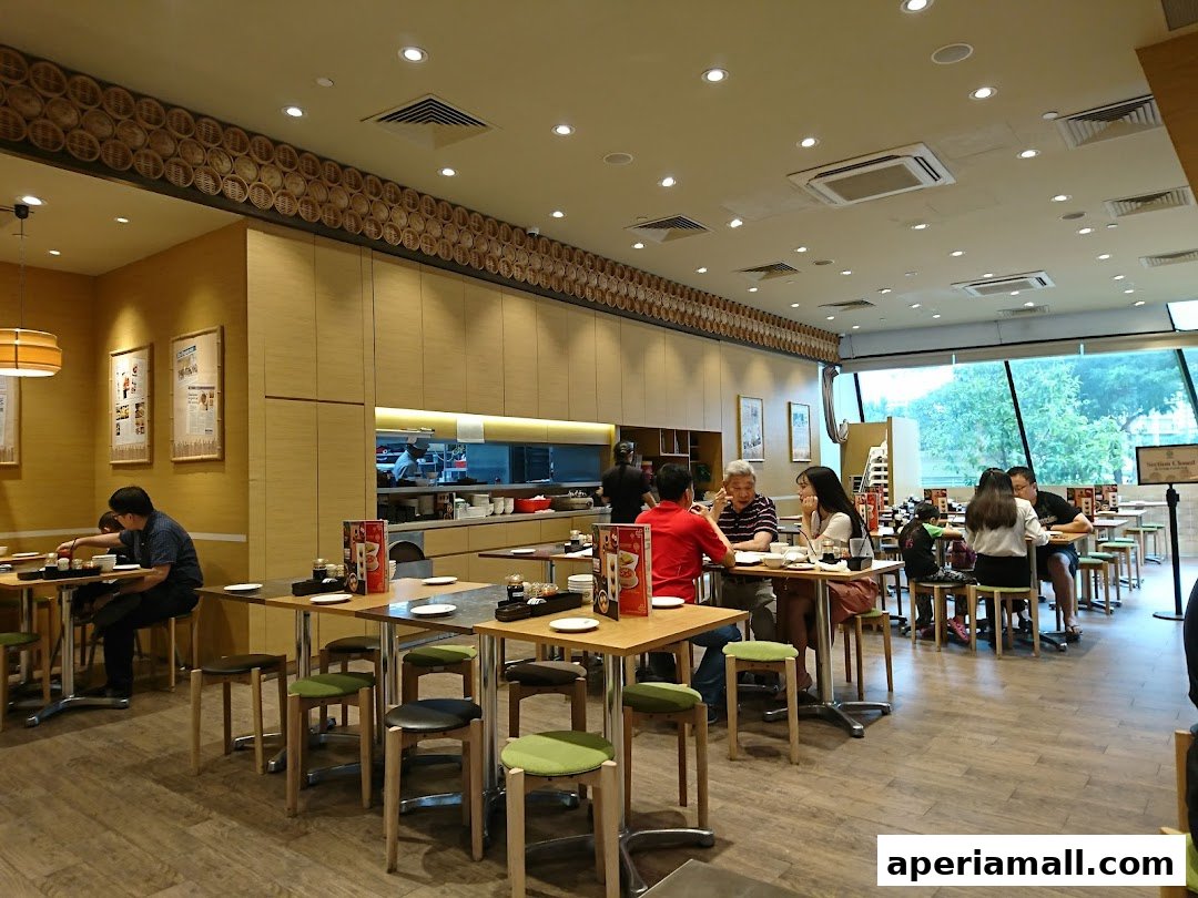 Interior view of a busy Tim Ho Wan restaurant with diners seated at tables.