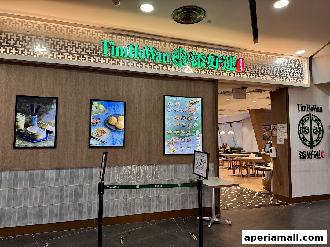 The entrance to Tim Ho Wan restaurant, featuring its signage and decorative wall art.