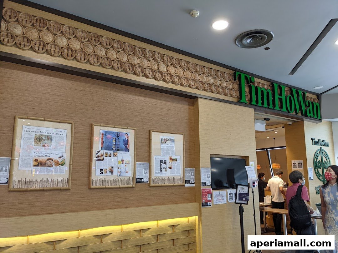 The entrance to Tim Ho Wan, a dim sum restaurant, with its prominent green signage and decorative bamboo steamers.