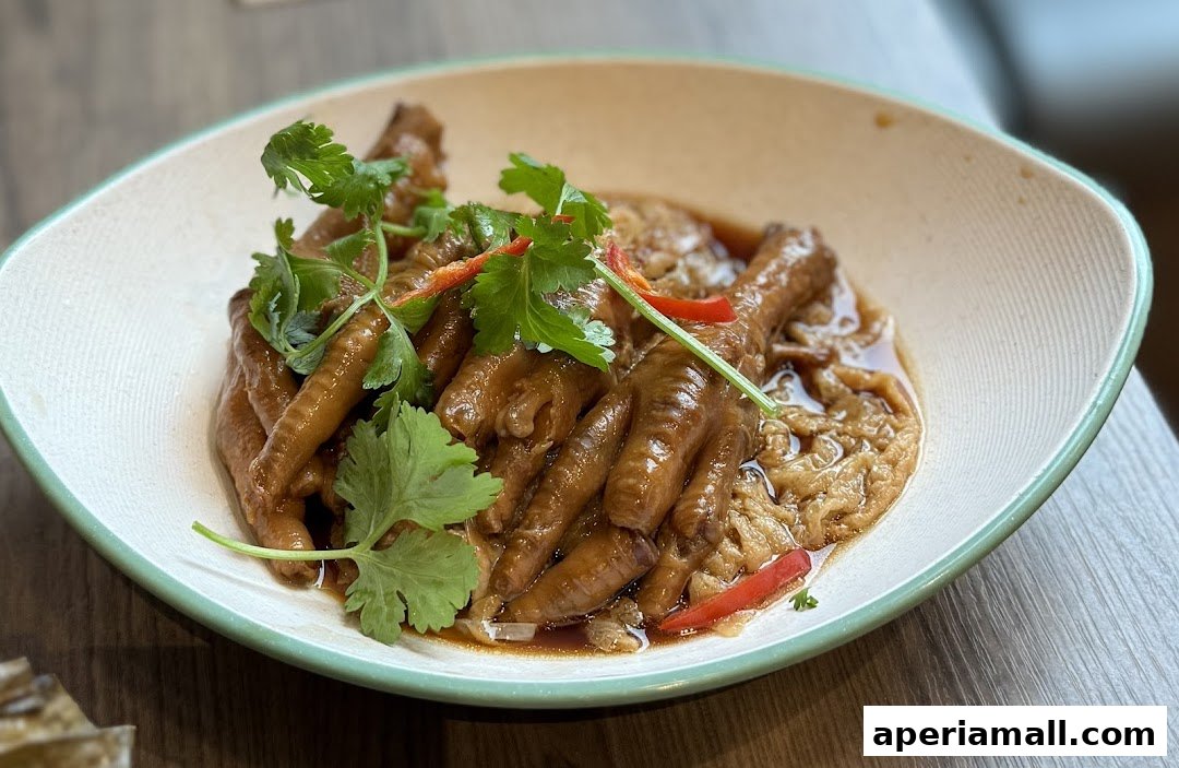 A close-up of a bowl of braised chicken feet, garnished with cilantro and chili.