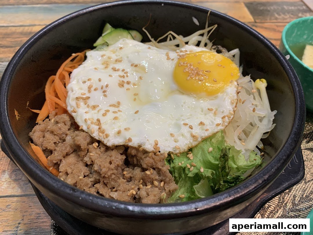 A close-up of a bibimbap dish with a fried egg, minced meat, and vegetables.