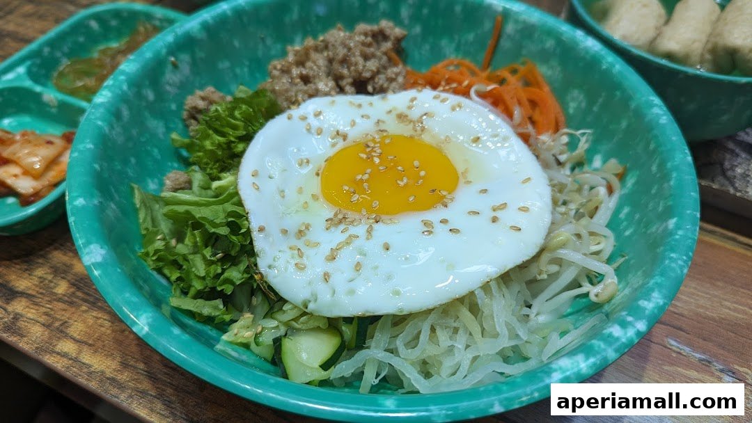 A close-up of a delicious bibimbap with a fried egg, vegetables, and meat in a green bowl.