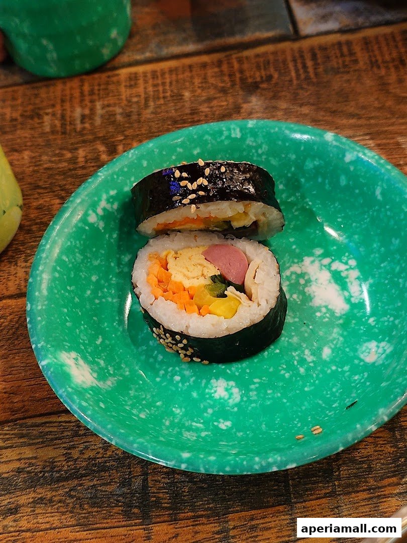 A close-up shot of two pieces of kimbap on a green speckled plate.