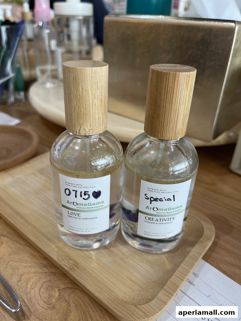 Two bottles of AromaGems essential oils with wooden caps on a bamboo tray.