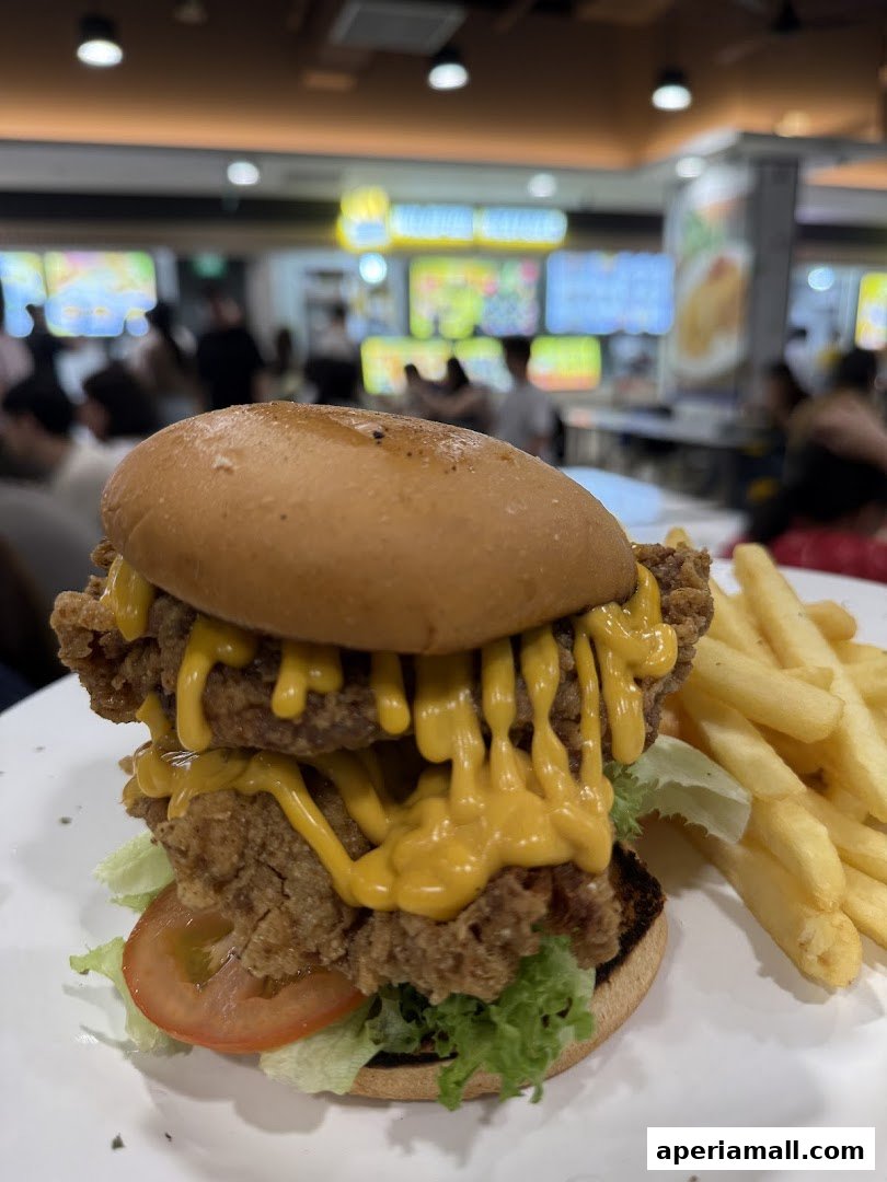 A close-up of a double-patty burger with cheese and fries on a white plate.