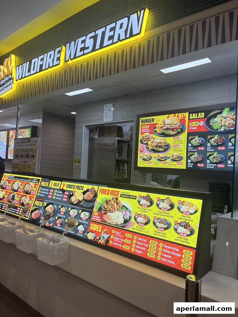 A brightly lit food stall with a large menu displaying various Western dishes like burgers, pasta, and fried rice.
