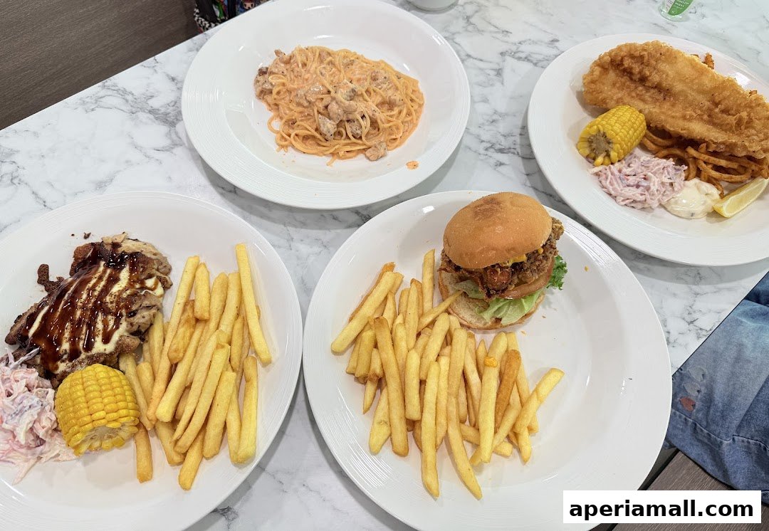 A table laden with four plates of food: pasta, fish and chips, a burger, and chicken with fries.