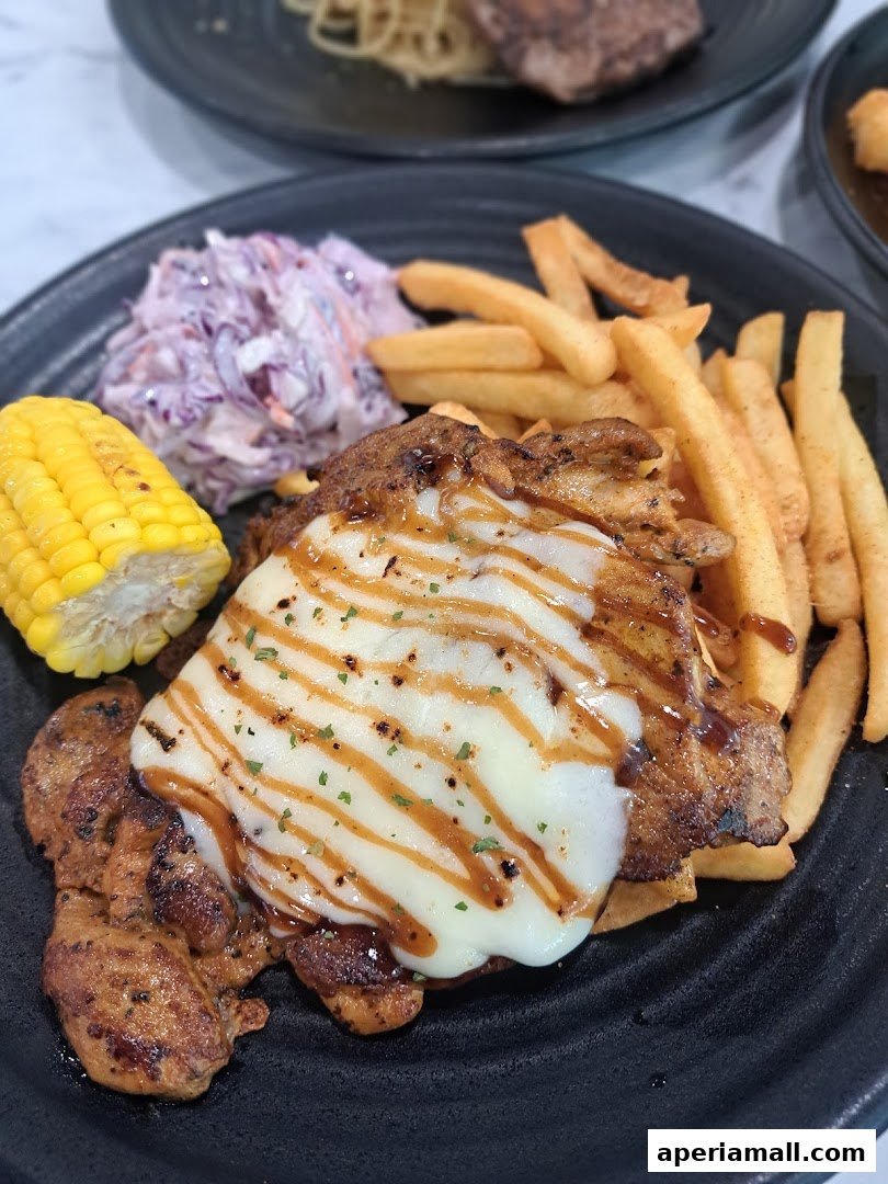 A plate of grilled chicken with melted cheese, fries, coleslaw, and corn on the cob.