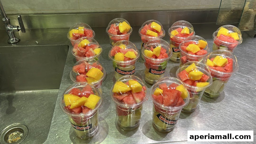 Several cups of fresh fruit salad, featuring watermelon and mango, are neatly arranged.