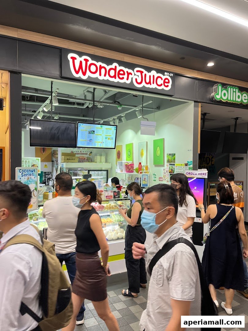 People walking past a Wonder Juice shop with a Jollibee next door.
