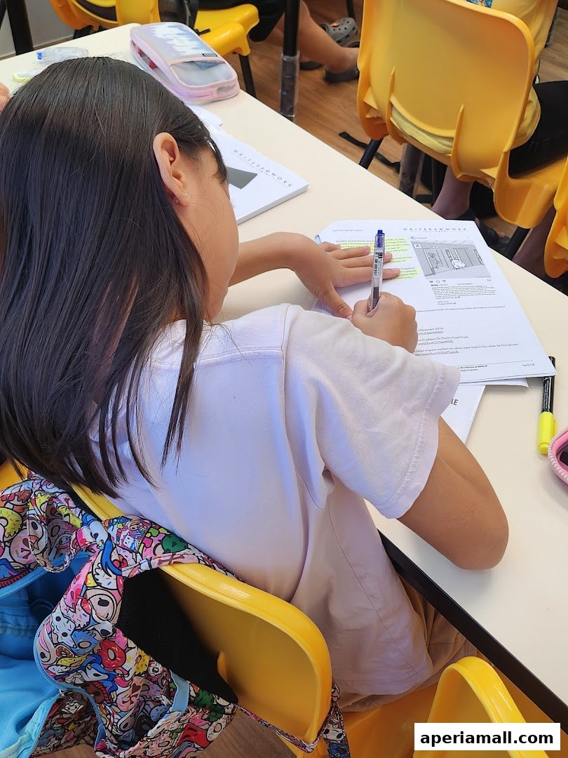 A young girl is focused on writing and highlighting text in a workbook at a table.