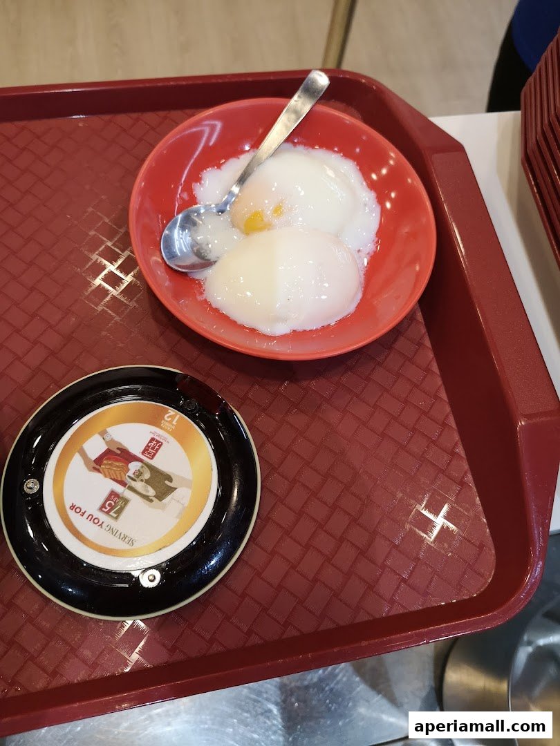 A tray with a bowl of soft-boiled eggs and a call button from Ya Kun Kaya Toast.