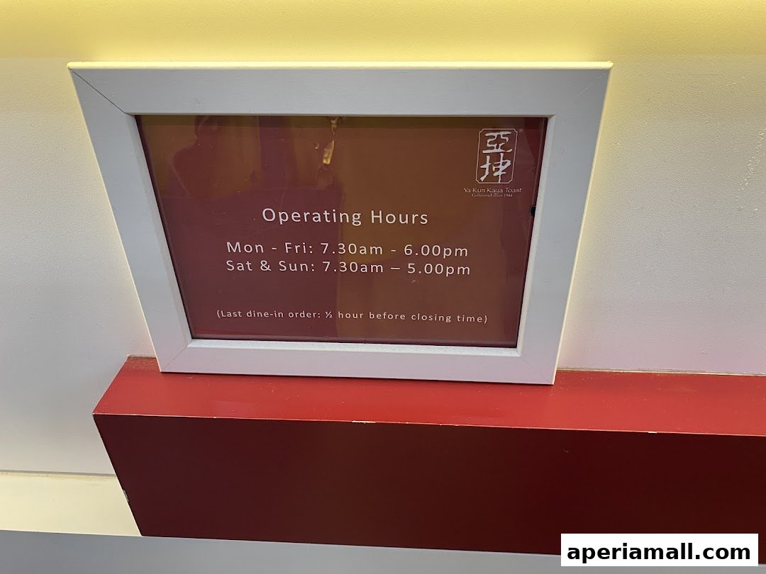 A framed sign displaying the operating hours for Ya Kun Kaya Toast.