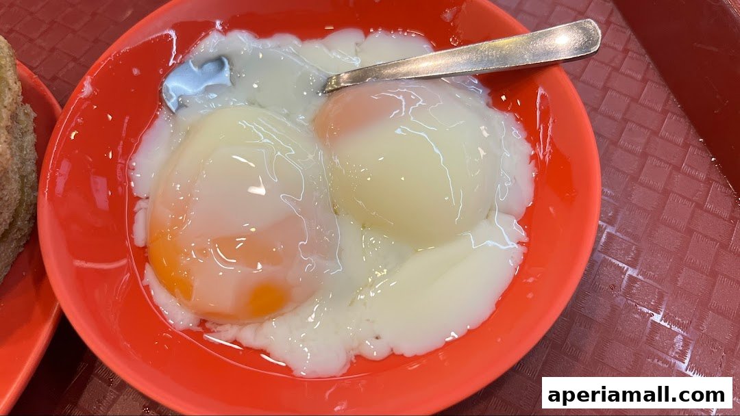 A close-up of two perfectly soft-boiled eggs in a red bowl with a spoon.