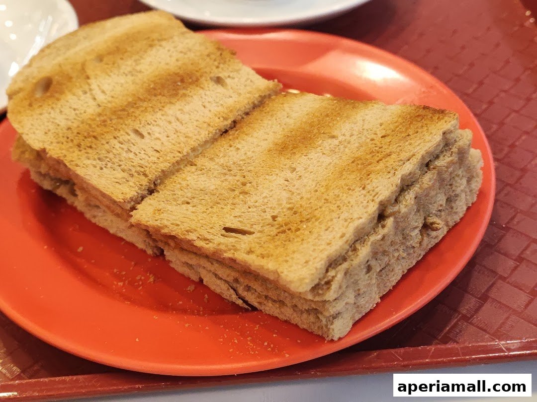 A close-up shot of kaya toast served on a bright orange plate.