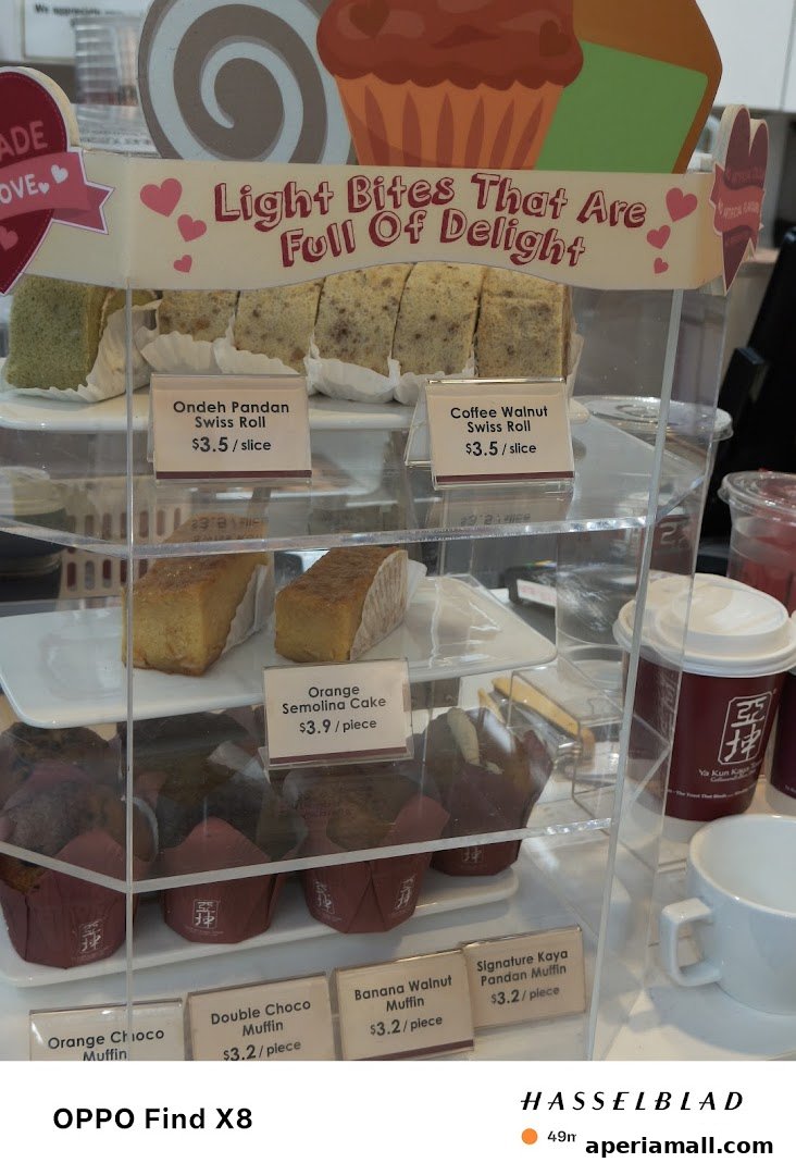 A display case filled with various pastries and muffins from Ya Kun Kaya Toast.