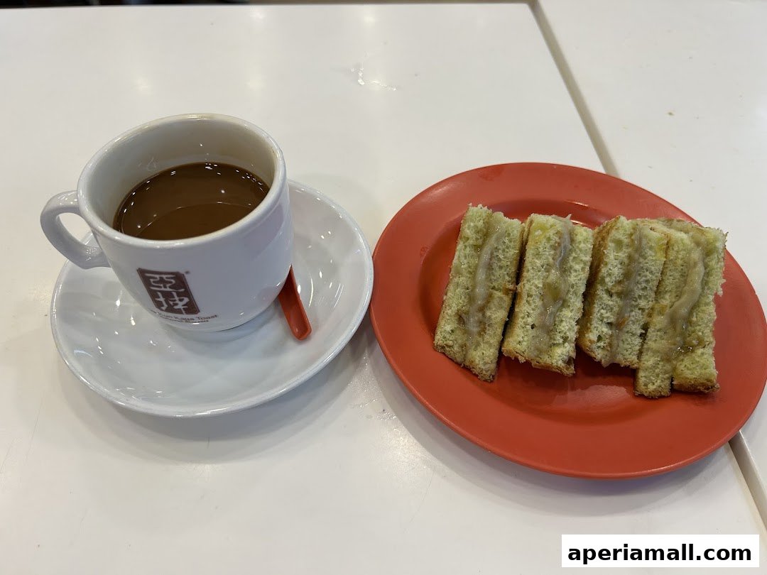 A cup of coffee and kaya toast slices on a white table.